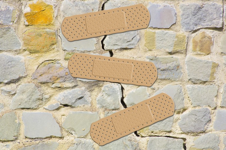 Old cracked and damaged stone wall cause due to subsidence of foundations structural failures - concept with adhesive bandage