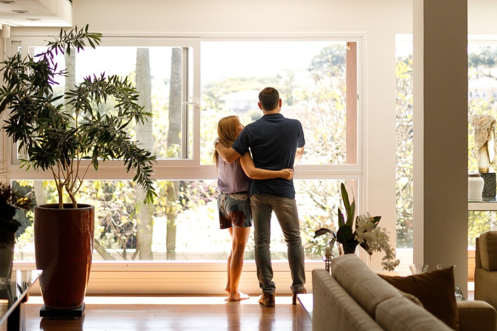 couple-admiring-the-view-from-the-living-room-of-their-house-picture-id1146103884